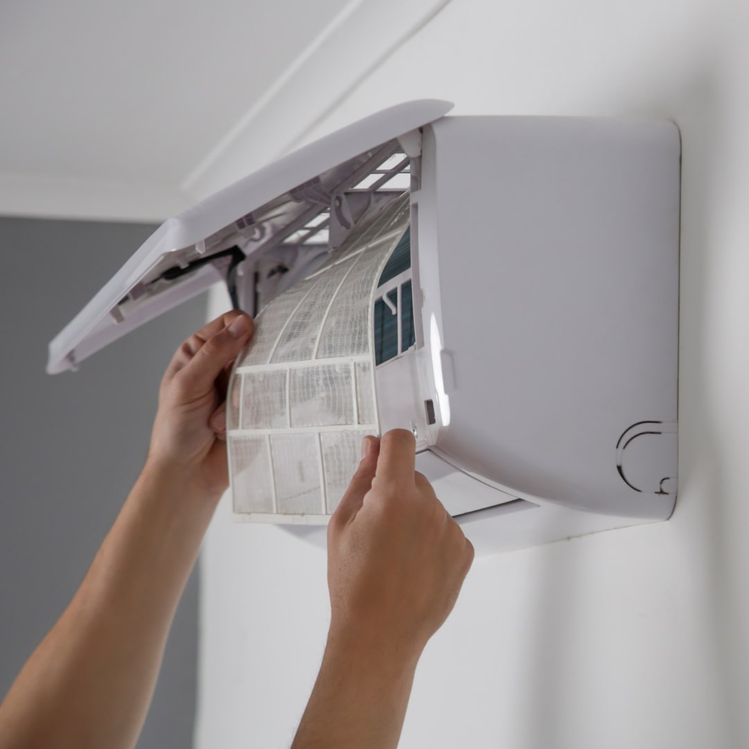 photo of a man replacing a filter in a air con